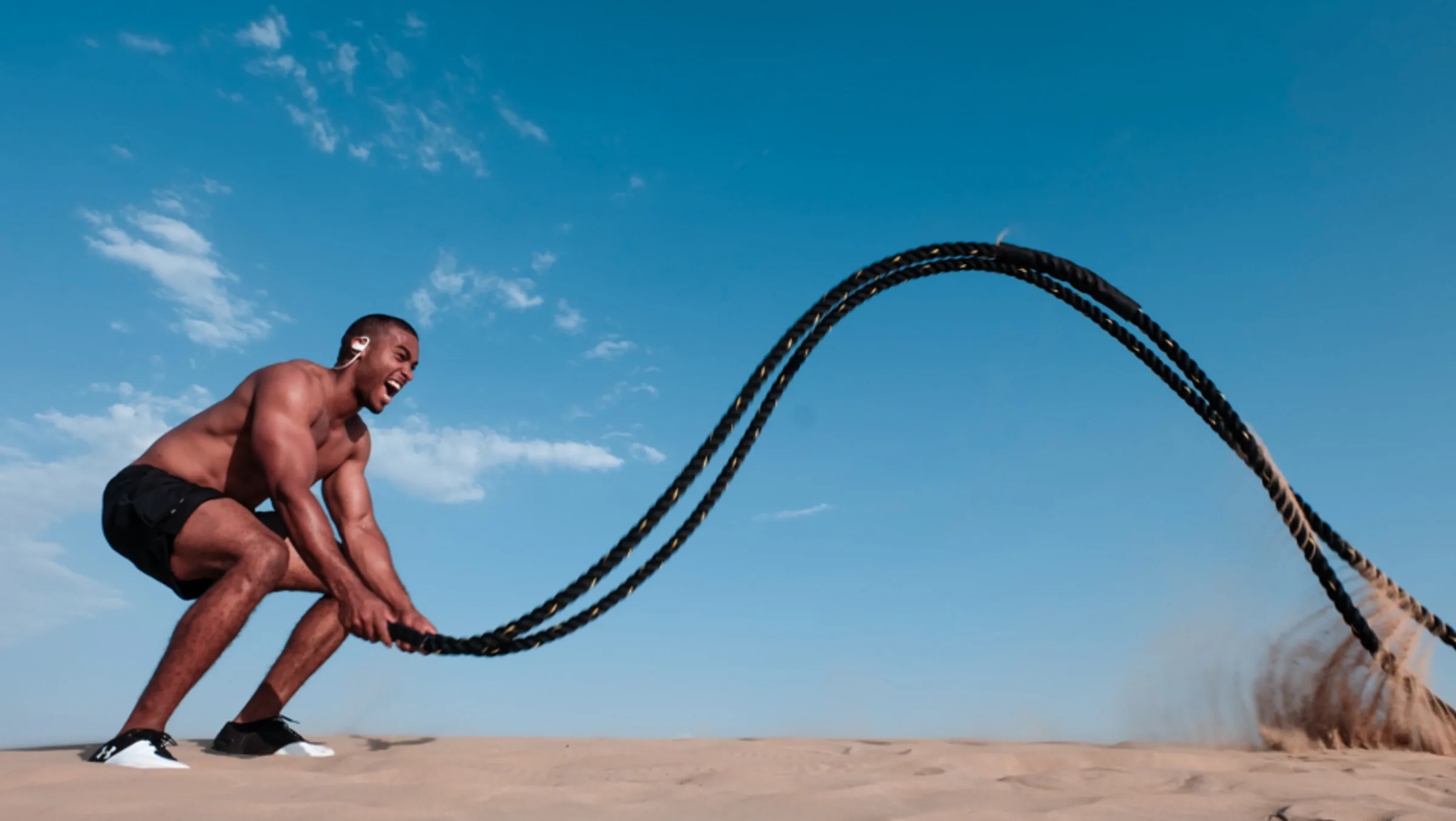 An athlete training with battle ropes on sand