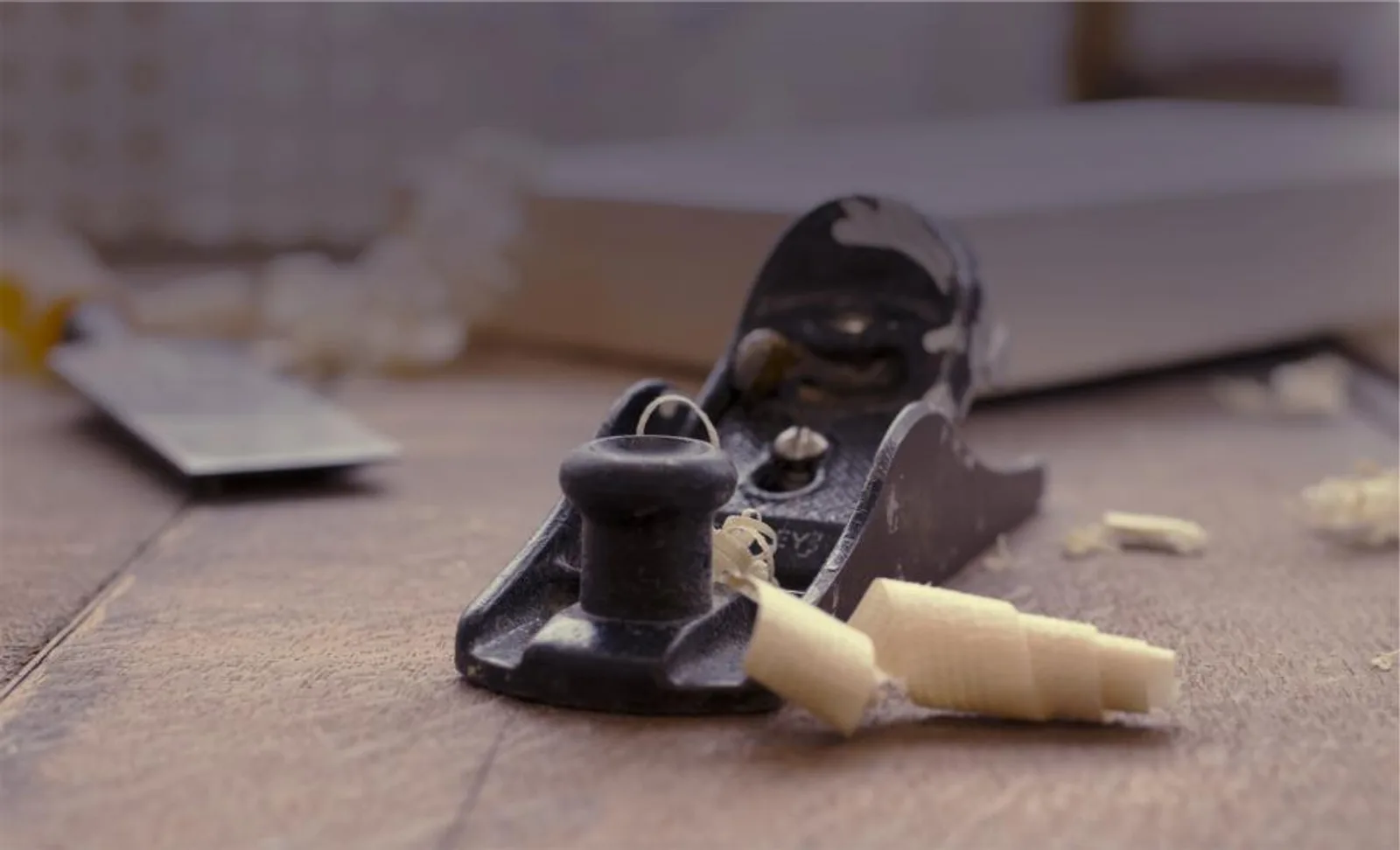A hand plane and wood shavings on a workbench
